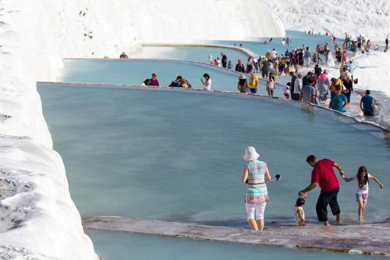 Du khách lội chân trần trong vũng nước nông trên bậc thang đá vôi Pamukkale